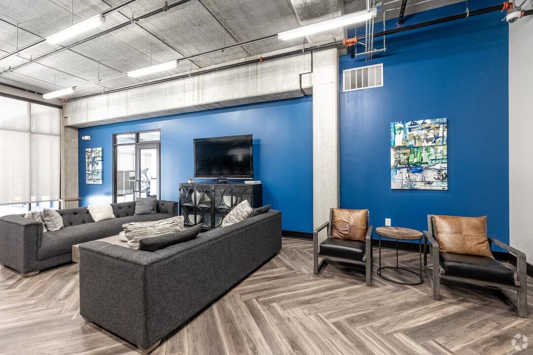 One-bedroom living room with tall windows overlooking a historic brick building on Court Avenue