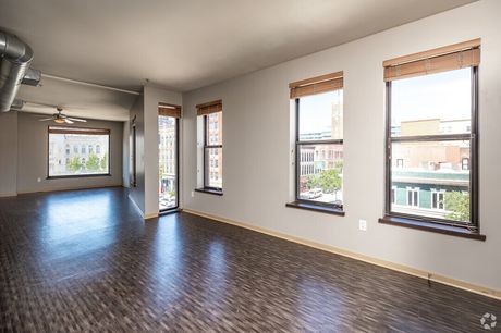 A bedroom with tall windows and dark wood-look flooring