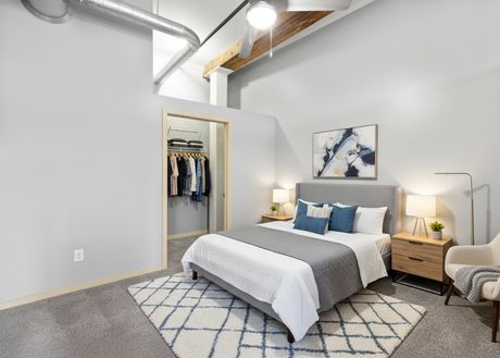 A furnished bedroom with a queen bed and walk-in closet