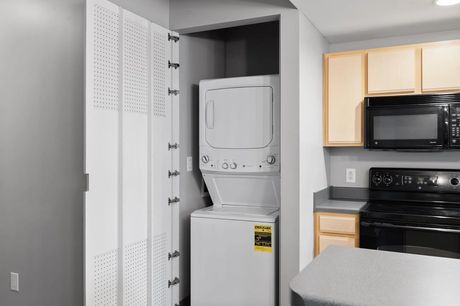 An in-unit stacked washer and dryer next to the kitchen